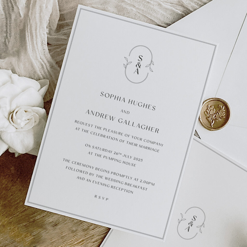 Eden Monogram - simple elegant monogrammed wedding invitation shown with matching envelope and wax seal on a wooden background