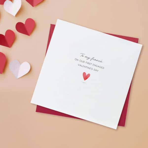 Fiance valentines day card on a peach background, also showing a red envelope. The words to my fiance on our first engaged valentines day are printed on the front. the card is white