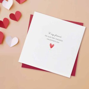 Fiance valentines day card on a peach background, also showing a red envelope. The words to my fiance on our first engaged valentines day are printed on the front. the card is white